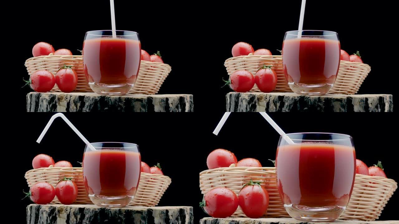 用吸管将番茄汁放入玻璃杯中。黑色背景木板上的新鲜西红柿