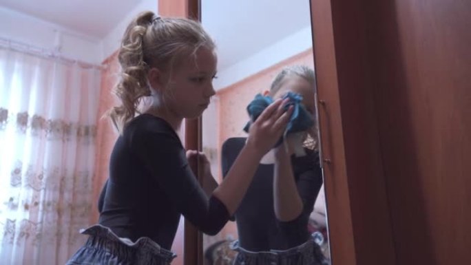一个学龄女孩正在打扫她的公寓。她勤奋地擦拭壁橱镜子，帮助父母打扫房子。