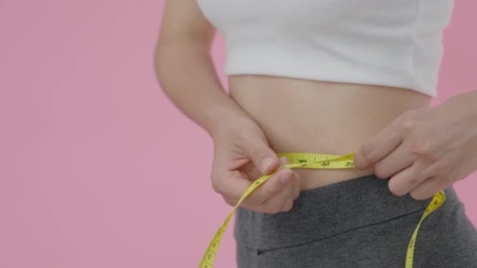 女人在弄脏后表现出苗条的身材，并用胶带测量她的腰部。健康护理、减肥和饮食理念。