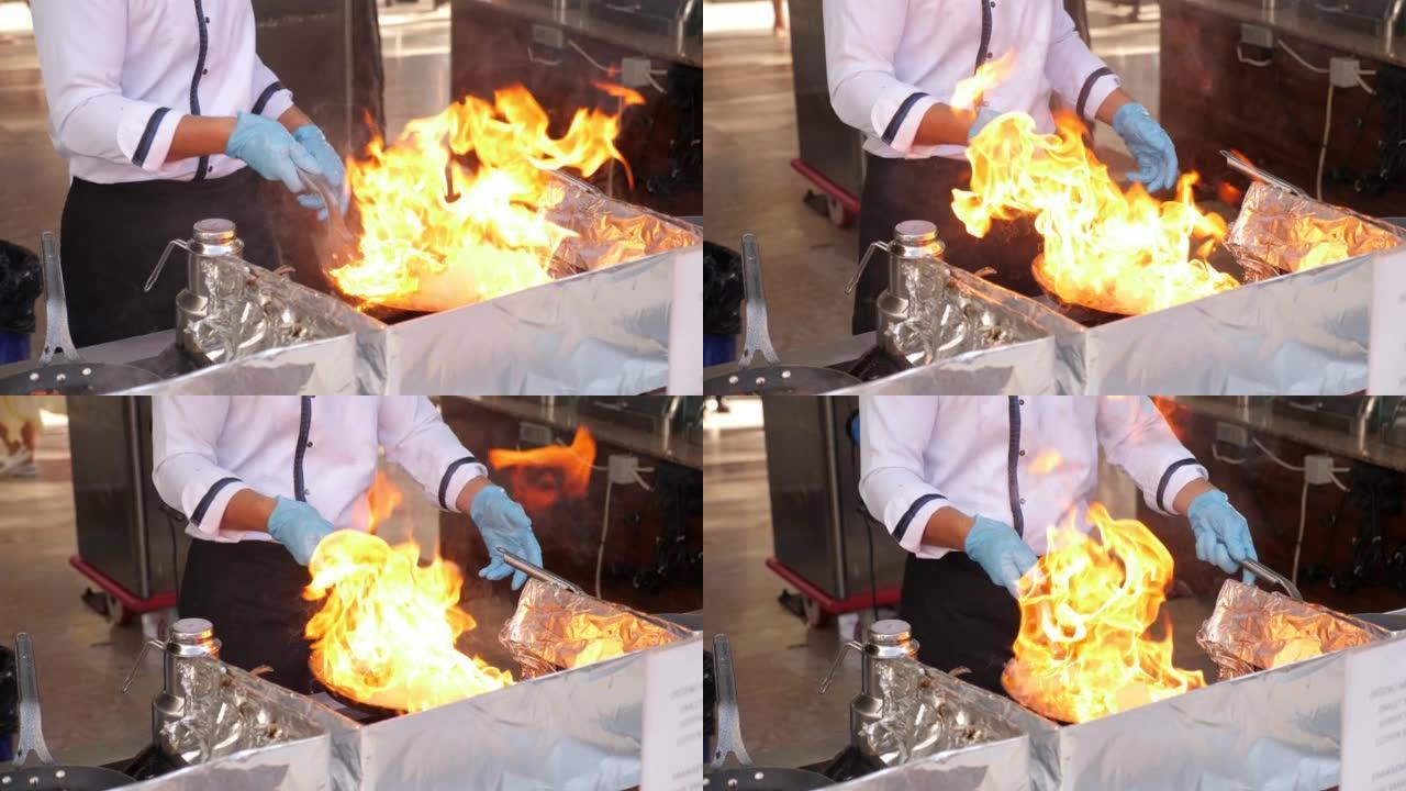 餐厅厨师在室外厨房着火做饭的特写镜头。