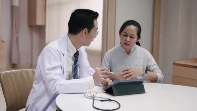 资深亚洲妇女听取医生对儿子病情的建议。