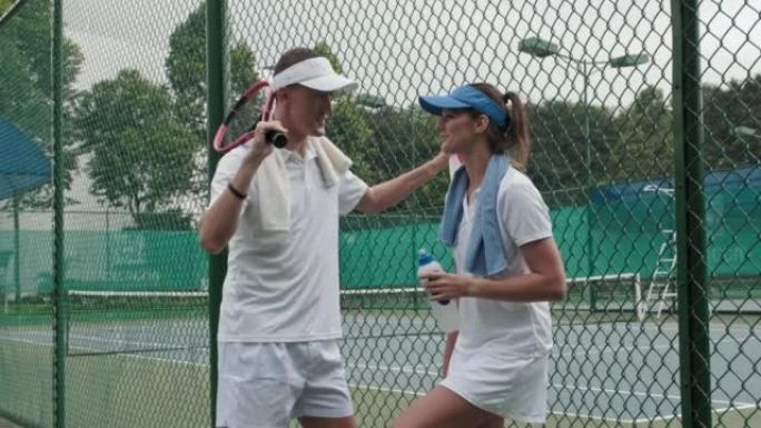 夫妇在室外球场打网球后聊天