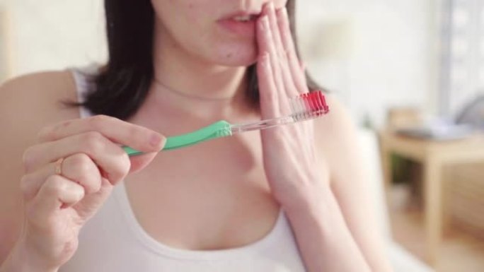 关闭年轻女子注意到刷牙时刷子上有血，口腔疼痛