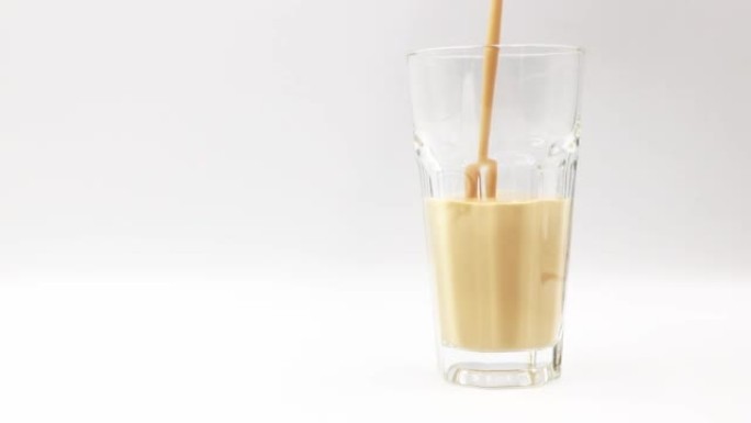 将咖啡味的牛奶倒入白色背景上的玻璃杯中。