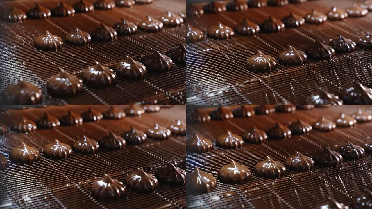 巧克力涂层中的闪亮棉花糖沿着传送带移动。工厂自动生产糖果。特写。