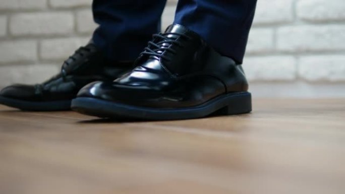 主人用脚踩在地上，男鞋是经典的黑色，男鞋是现代的。用脚敲地板。身体的语言