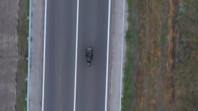 摩托车手在乡村公路上骑摩托车的俯视图。男人在旅行中驾驶自行车。在乡村路线骑现代运动摩托车的自行车手的