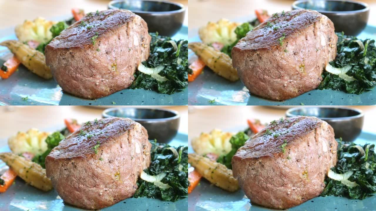 烤牛肉里脊肉牛排放在蔬菜蓝盘上。蔬菜菲力牛排食谱