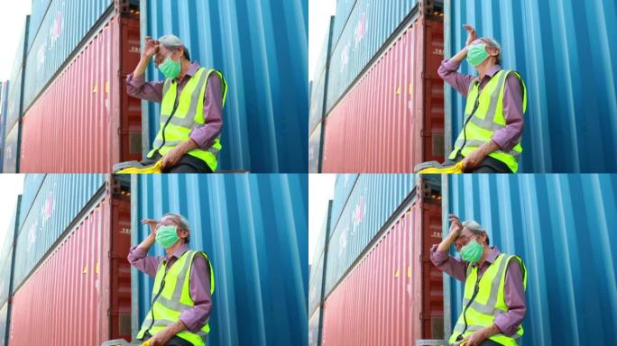 疲惫的亚洲高级男性集装箱工人戴着防护面罩、安全帽和制服。人牵手疼痛发炎，手腕肌腱炎。