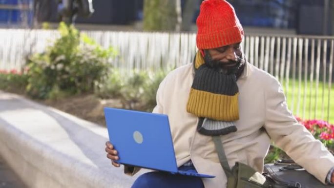 成熟的男人在冬季公园使用笔记本电脑和喝咖啡