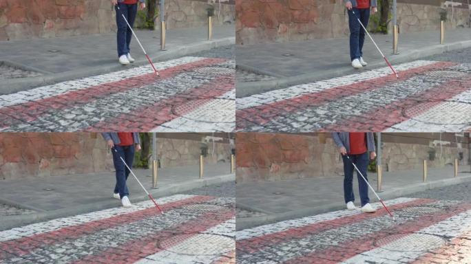 年轻盲人在户外独自行走时使用安全棍。一个盲人拄着拐杖过马路