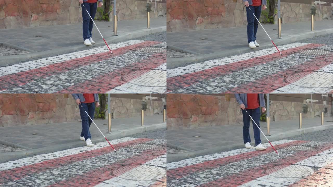 年轻盲人在户外独自行走时使用安全棍。一个盲人拄着拐杖过马路