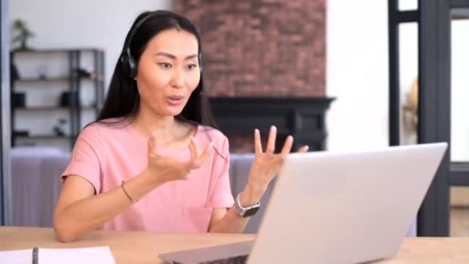 一位迷人的年轻亚洲女性正在使用笔记本电脑进行室内视频通话