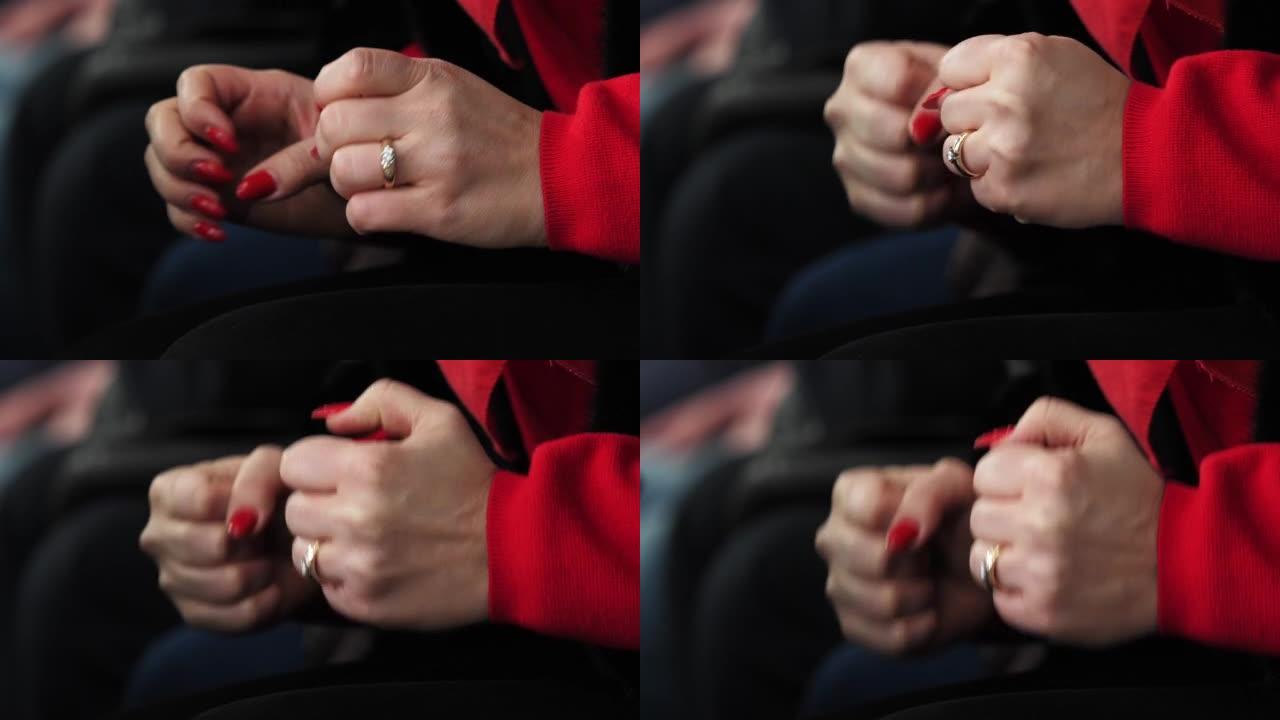 红色修指甲的女性支持者用拳头轻拍膝盖