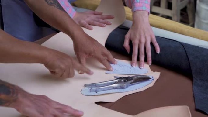 4K，手近距离手工制作的皮革放置鞋形纸板，熟练的工匠铺纸，在牛皮上绘制将牛皮切成鞋形，可根据客户要求