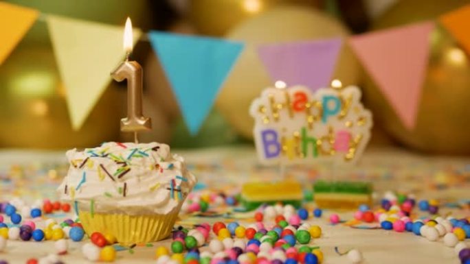 令人难以置信的美丽1岁孩子的生日背景，奶油纸杯蛋糕与燃烧的蜡烛，烟火和气球的背景。1岁宝宝生日背景视