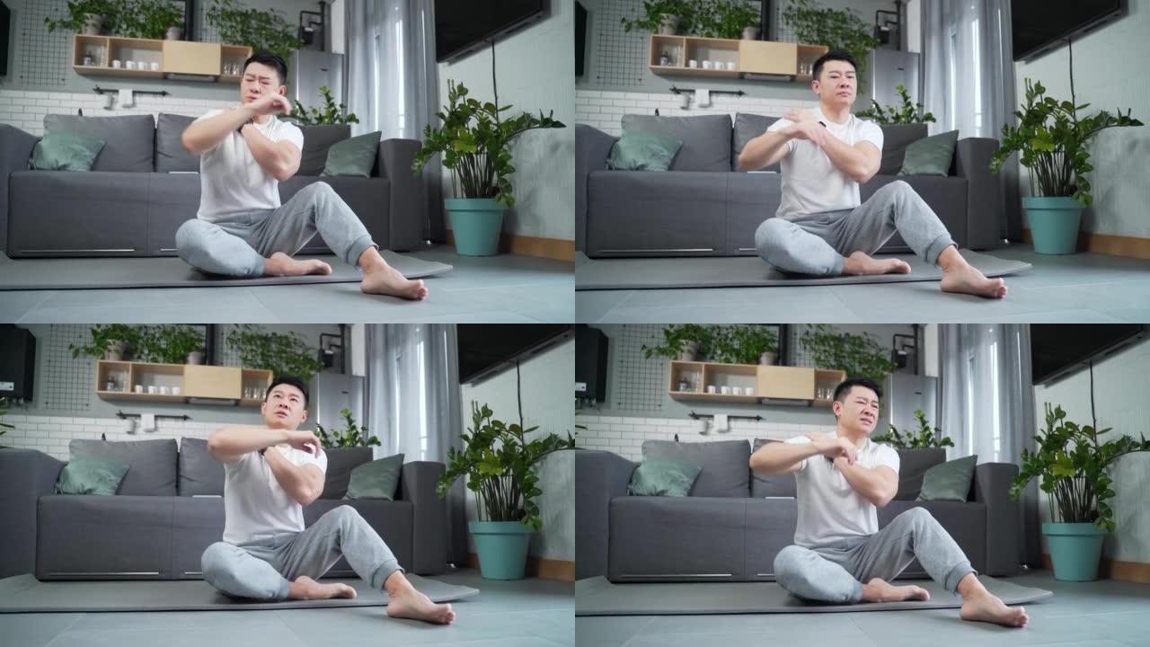 亚洲年轻人在室内锻炼伸展背部疼痛。运动健身男性痛苦感觉突然疼痛肩和关节肌肉劳损