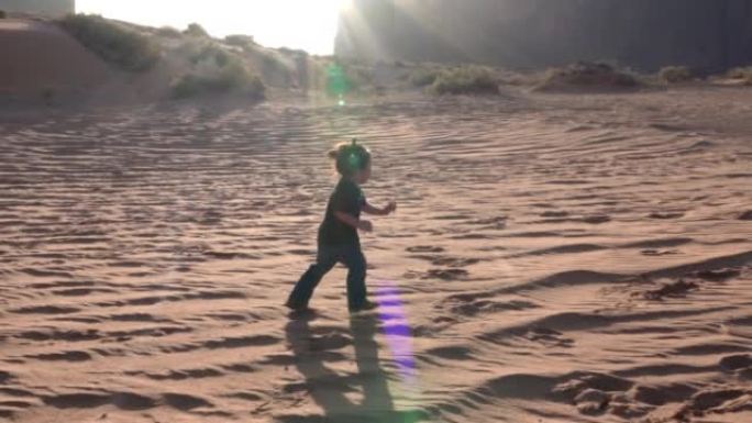 年轻的母亲和她蹒跚学步的儿子在亚利桑那州纪念碑谷的家附近的沙丘上玩耍和奔跑