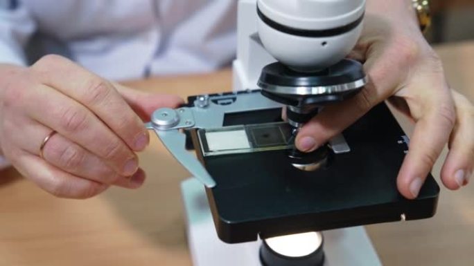 实验室研究人员将样品放在显微镜下。现代医院的医学实验室。特写。