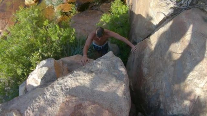 男子攀登南非瀑布池上方的阳光岩石