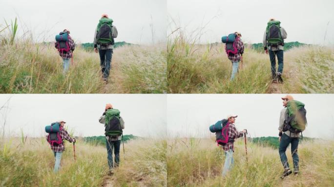 快乐的年轻夫妇徒步旅行者走过一片干燥的草地。年轻的男人和女人一起享受美好的时光。