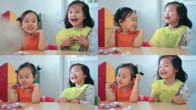 激动人心的亚洲中国蒙台梭利学龄前学生微笑着等待老师在艺术课的调色板上涂上水彩