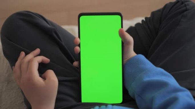儿童在客厅使用带有绿色模型的电话的观点。手机与绿色模拟屏幕色度键上网观看内容视频博客学习。玩电子游戏