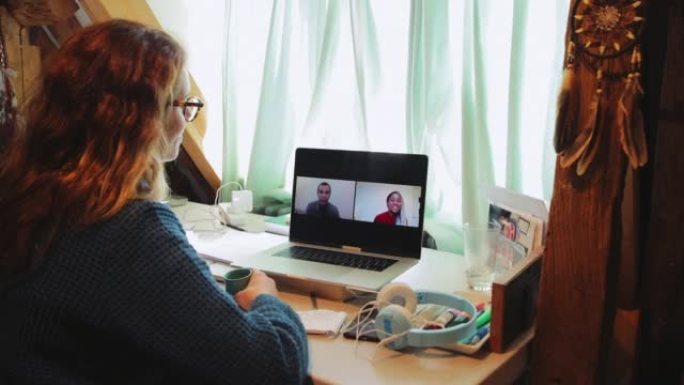 女性在家通过笔记本电脑屏幕与同事进行视频会议