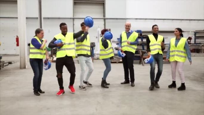 仓库工厂的多民族工人和工程师们欢欢喜喜地跳舞庆祝他们的成功。