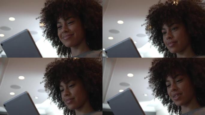 一位快乐的年轻女商人在现代办公室使用数字平板电脑。微笑的女商人在网上工作