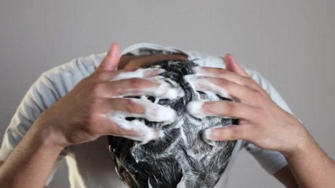 使用洗发水泡沫进行头发护理的男人