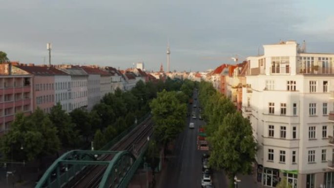 在Schoenhauser Allee街高架铁路上行驶的城市火车的前瞻性跟踪。上升的镜头揭示了清晨的