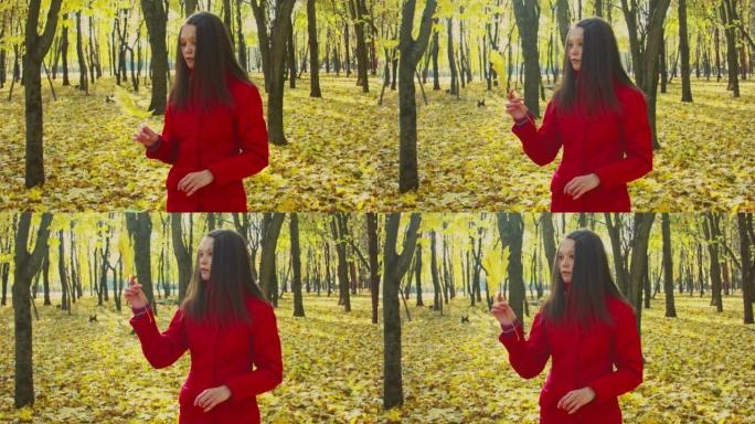 日落时，一个年轻女子拿着枫叶站在森林里的特写镜头。