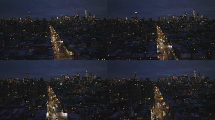 向前飞行在市区附近公寓之间的笔直而发光的街道上方。夜景城市景观，以市中心的摩天大楼为背景。美国纽约市
