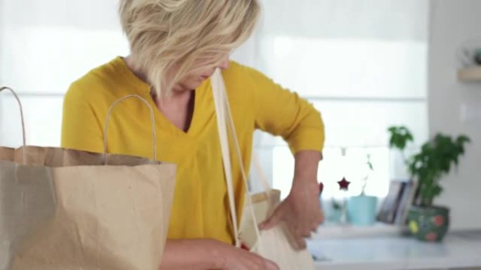 A woman returning home from the store carrying hea