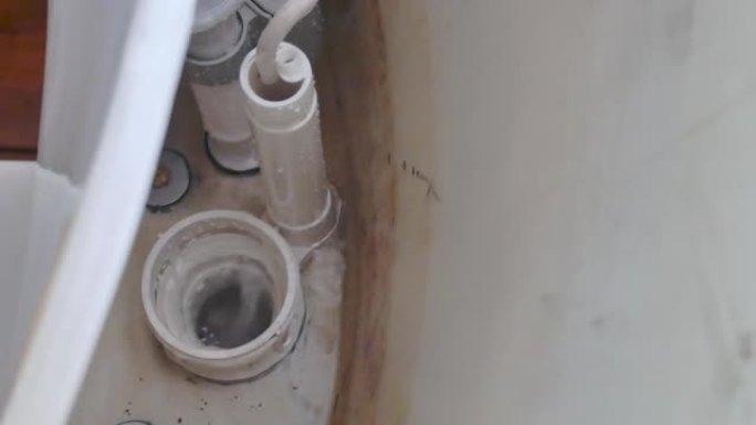 马桶水箱泄漏，缺少浮球和挡板机构故障。厕所维修，家庭维护，管道配件。查看白色陶瓷马桶水箱、碗和进气阀