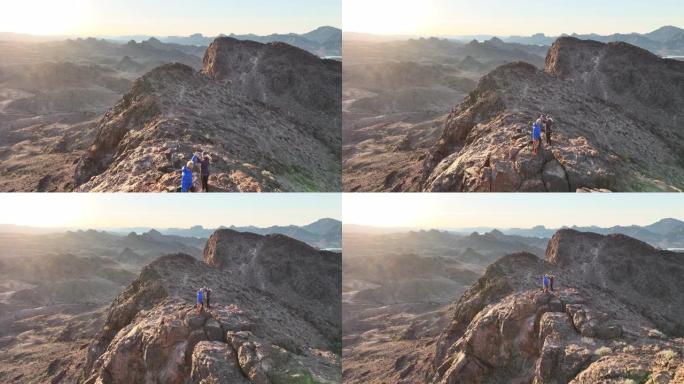 日出时成熟夫妇上升沙漠山脊的鸟瞰图
