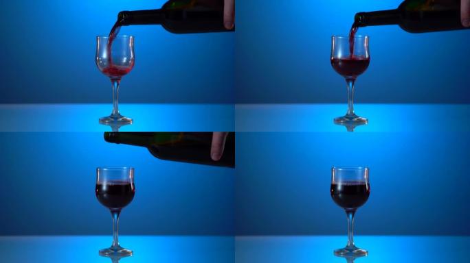 酿酒师正在用蓝色背景的玻璃杯倒红酒。酒精概念。美味的藤蔓。反映表。辛苦一天后喝一杯酒