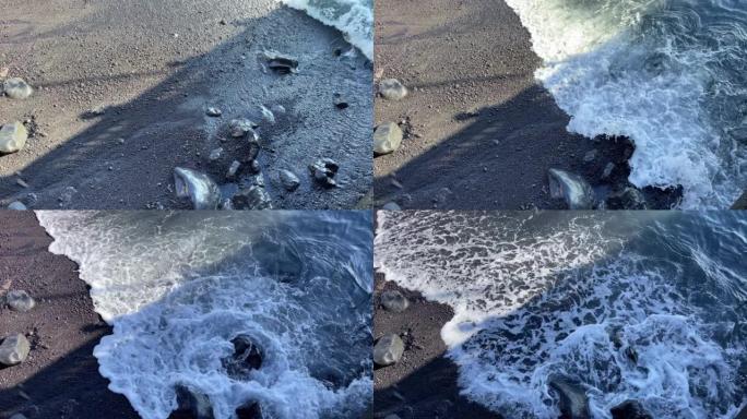 关闭在黑色沙滩上破裂的海浪的顶角。