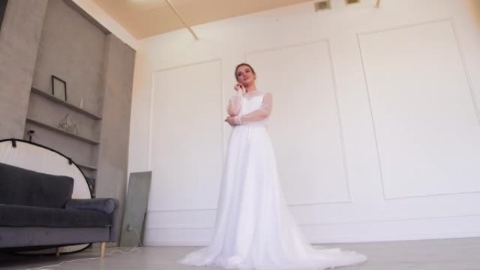 一个穿着白色婚纱的女孩摆姿势，用手臂拥抱自己。
