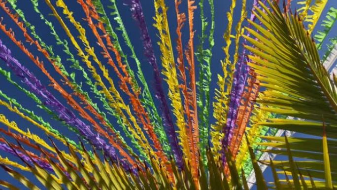 彩带装饰着蓝天和棕榈叶前的街道。假日概念。