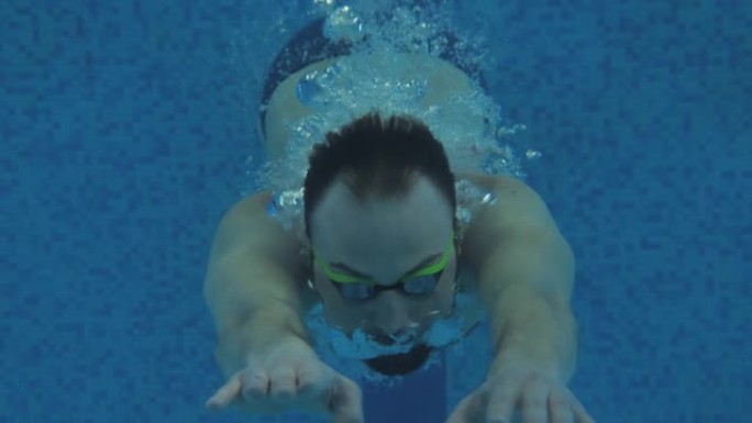 在游泳池进行护目镜训练的男性游泳者的水下肖像。游泳与运动概念