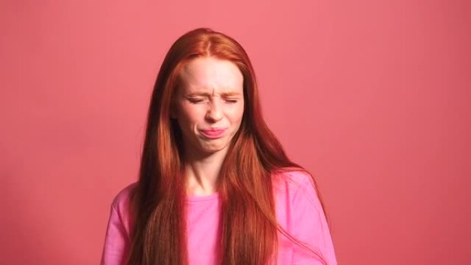 粉红色工作室背景下的红发姜女人感到尴尬和厌恶