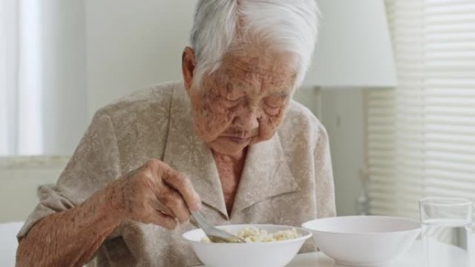 资深亚裔女子白发在疗养院吃食物