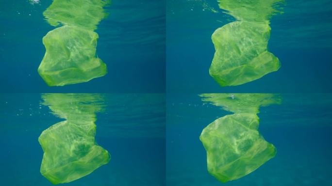 慢动作，黄色塑料袋在水下游泳，在阳光照着蓝色的水面反射。废弃的塑料袋在阳光照射下在水面下慢慢漂移。塑