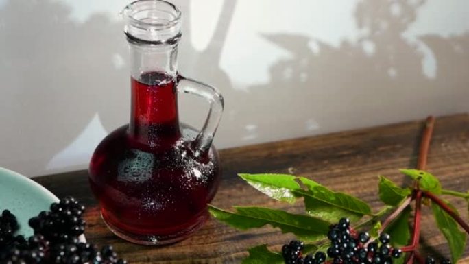 慢动作红汁瓶装，接骨木香草酊，黑浆果特写。浆果制成的治疗饮料