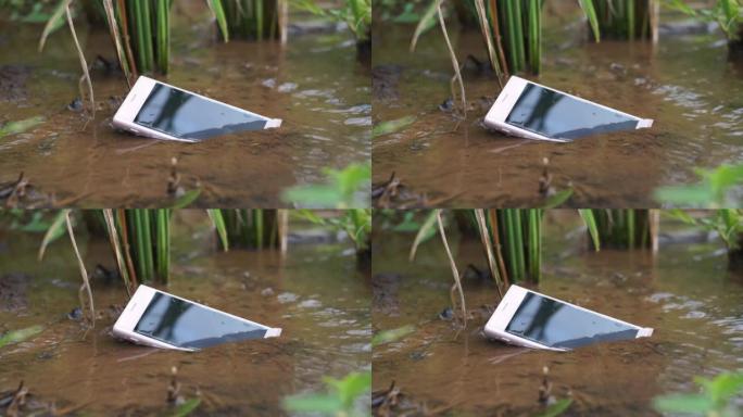 具有自然概念的泥土和绿草中的防水智能手机。IP68认证智能手机