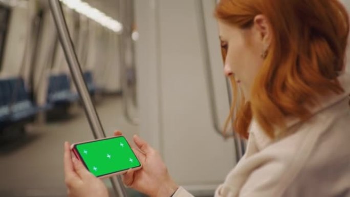 水平绿屏模拟智能手机，由观看地下交通在线网络研讨会的妇女持有。