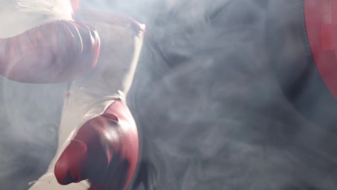 红色拳击手套和双端打击袋被烟雾包围。