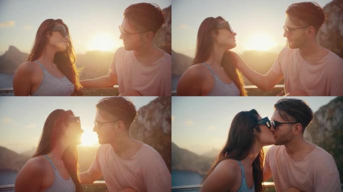 浪漫的夏天。夫妇在度假时戴着墨镜坐在长凳上，背景是金色的日落。热情的吻